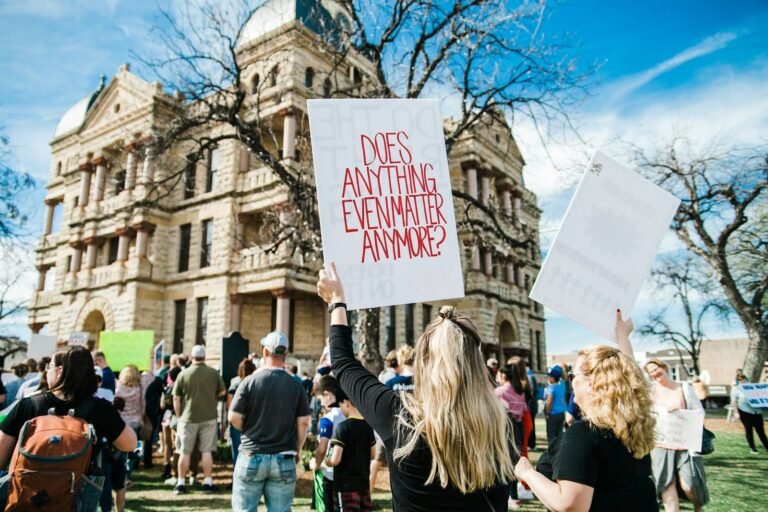 woman holding does anything even matter anymore? signage near building at daytime