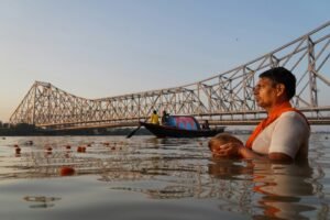 a man sitting in the water next to a bridge